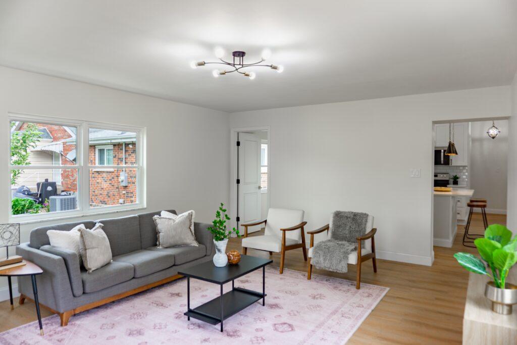 Living room with grey sofa, large windows, and wood floors