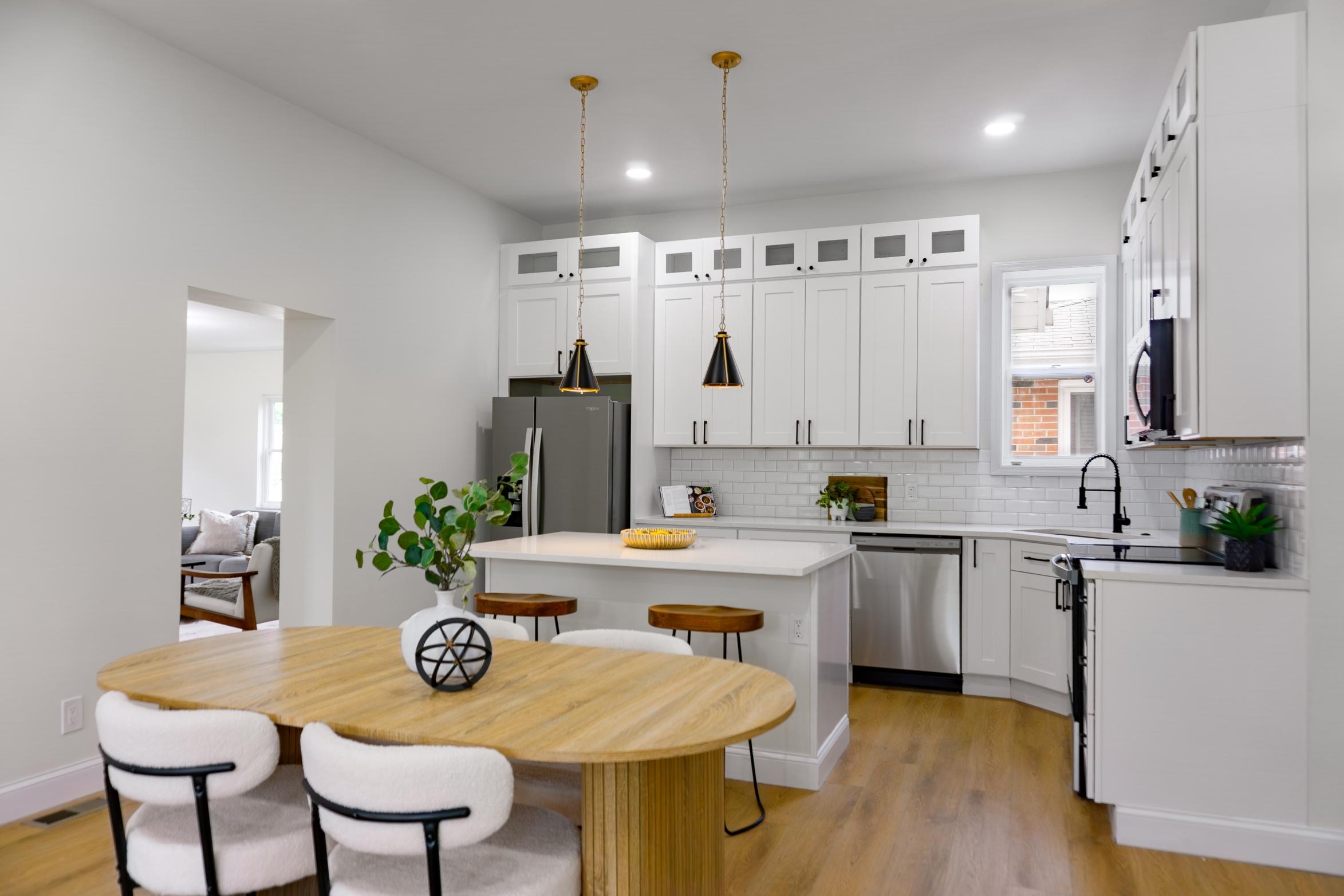 Open kitchen with island, white cabinets, wood dining table and 4 chairs