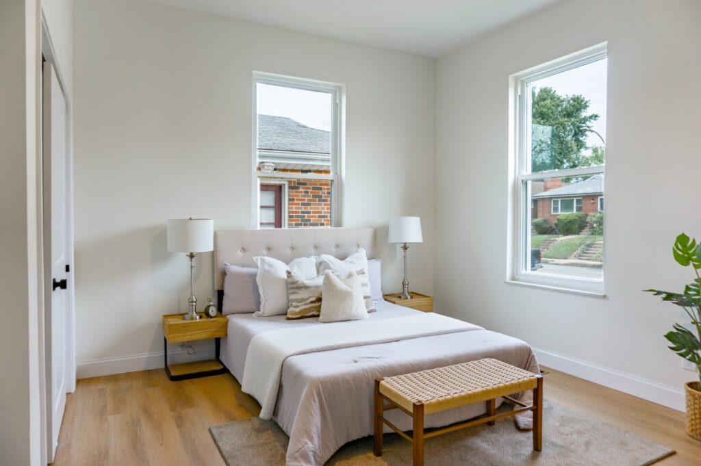 Primary bedroom with queen bed, neutral bedding, and two windows