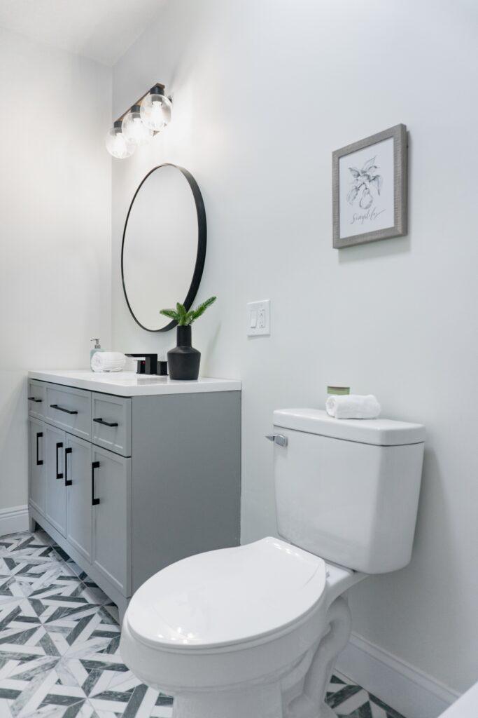 bathroom with grey vanity, black mirror and white walls