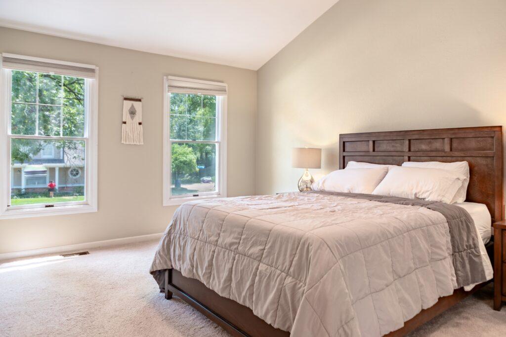 Primary bedroom with queen bed, neutral bedding, and two windows