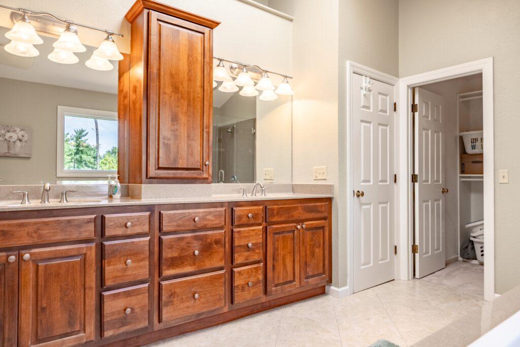Bathroom with double vanity, wood cabinets, and overhead lighting