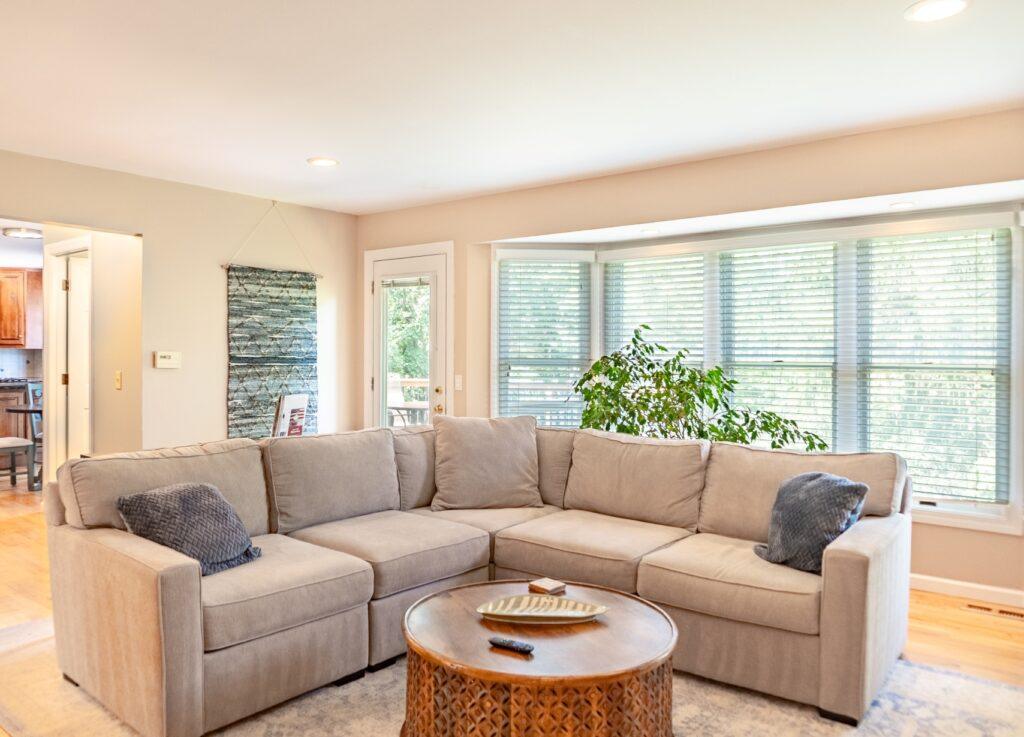 Living room with sectional sofa, large windows, and wood floors