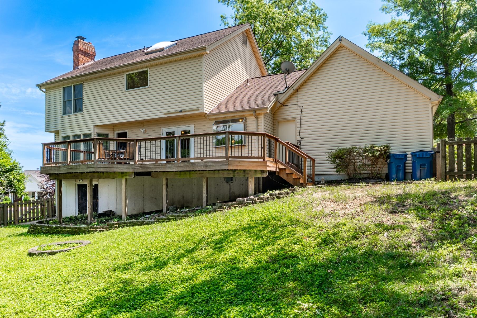 Rear exterior of home with elevated deck and grassy backyard