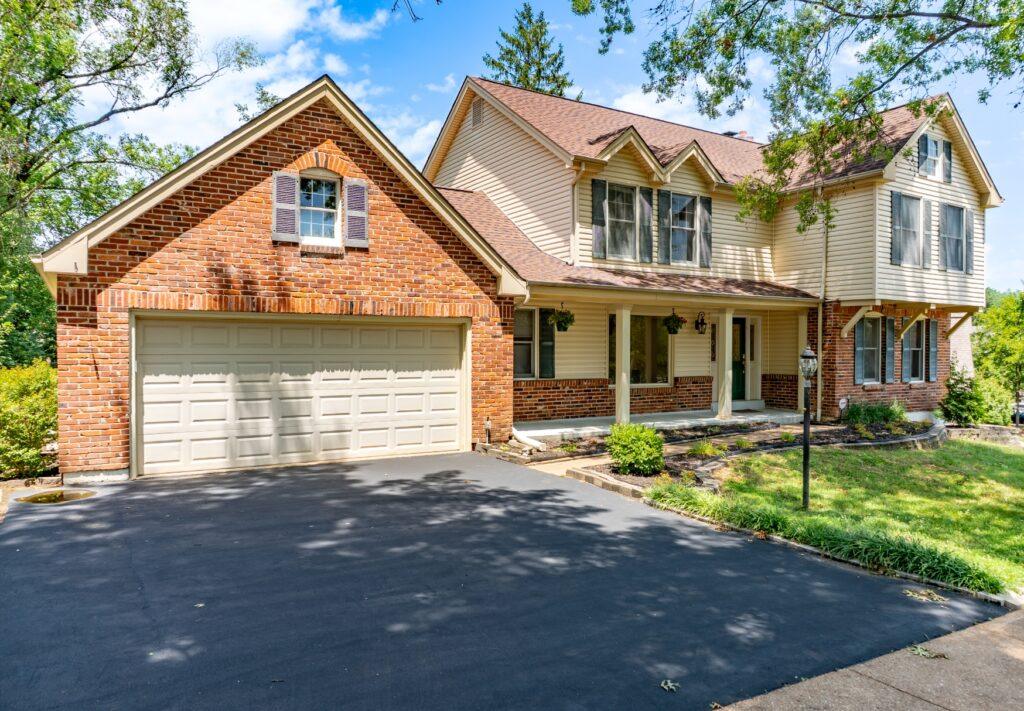 Two-story home with brick front, garage, and paved driveway