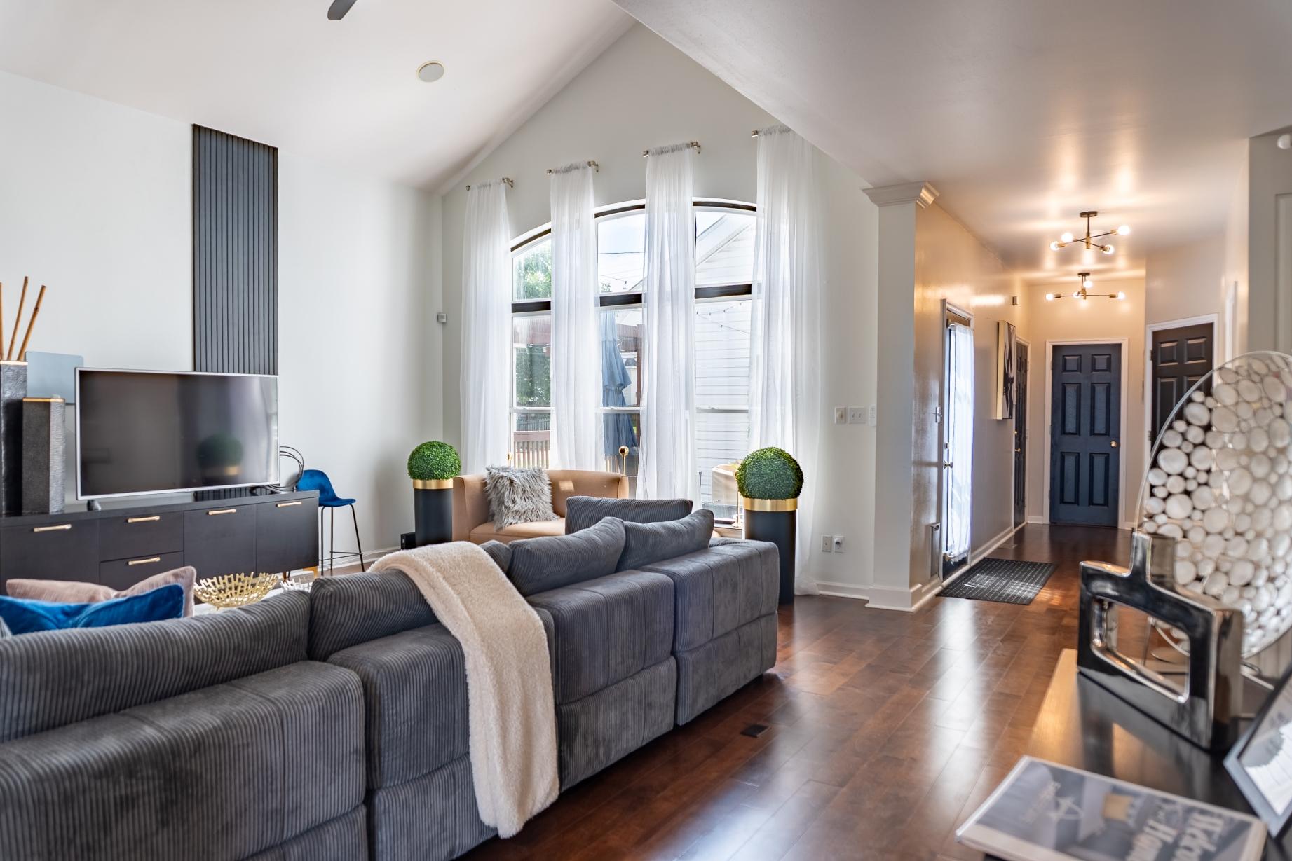 Living room with gray sofas, tall windows, and wood floors