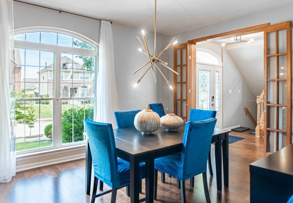 Dining room with blue chairs, modern chandelier, and large windows