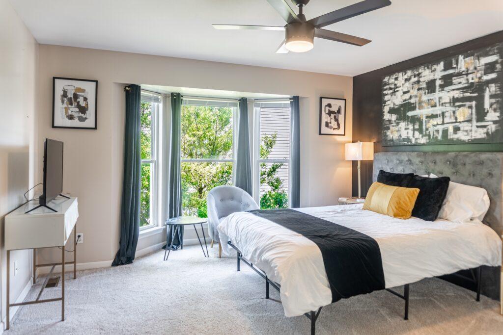 Bedroom with a bay window and white bedding with black accents