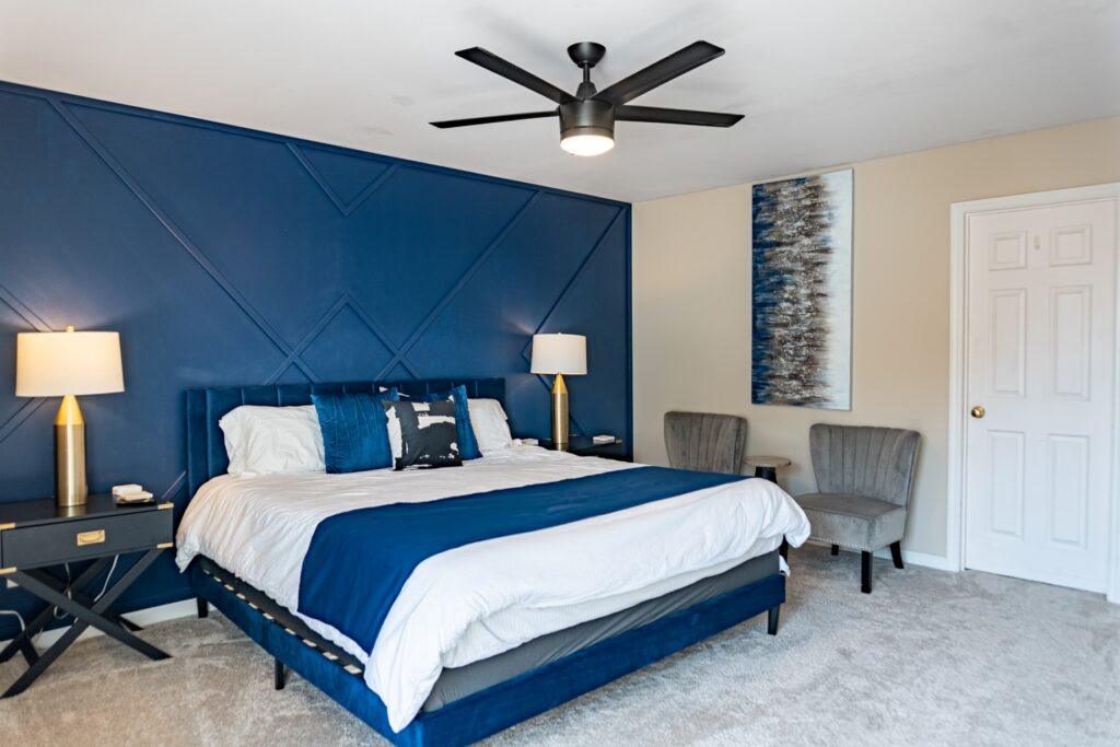 Primary bedroom with blue accent wall, king bed, and ceiling fan