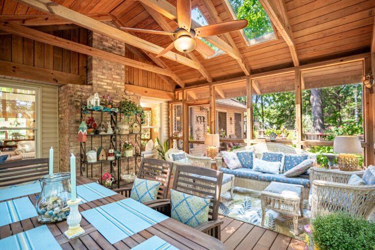 Covered porch with sofas, ceiling fan, and forest views