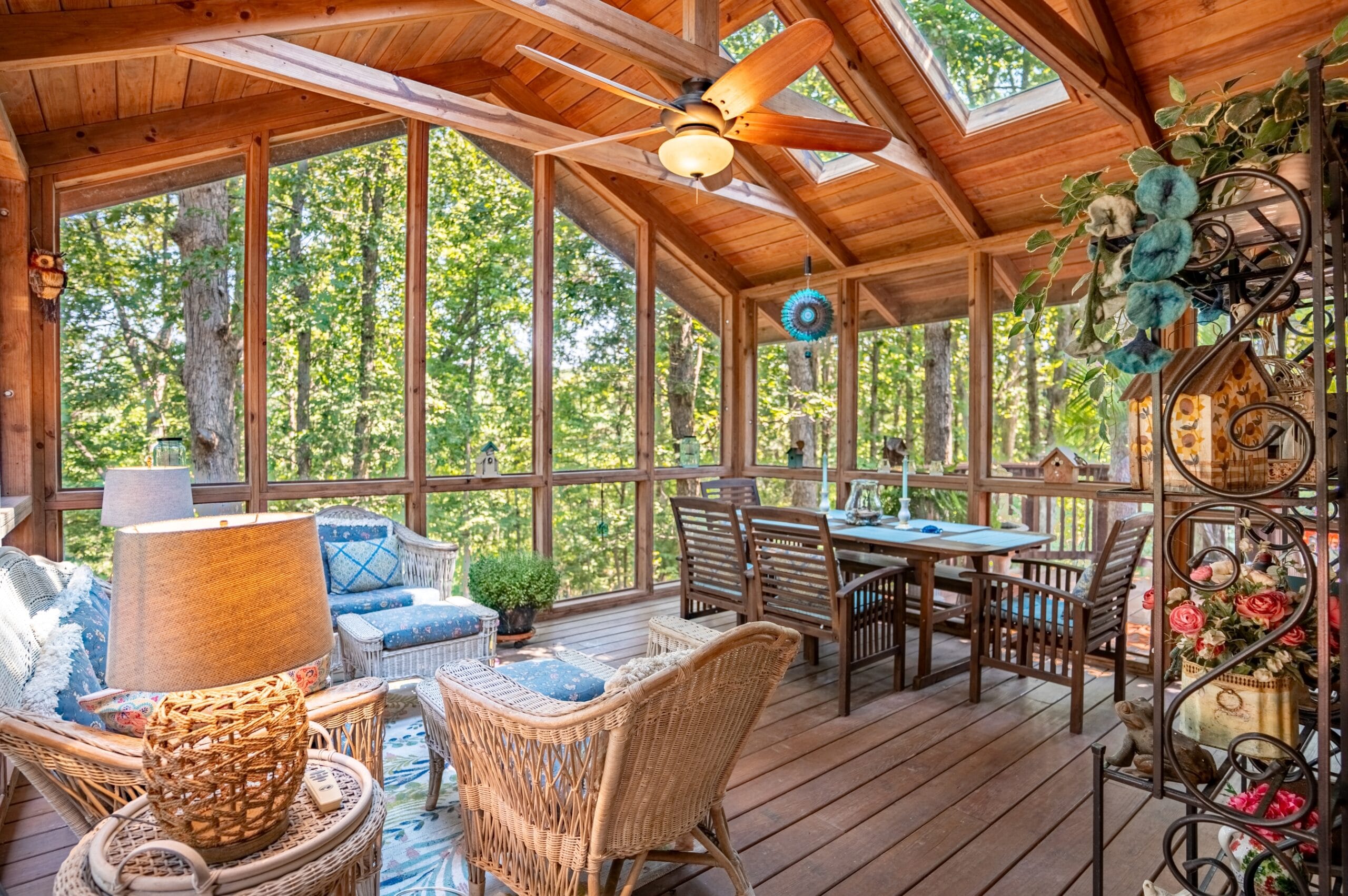Covered porch with wicker chairs, dining table, and ceiling fan