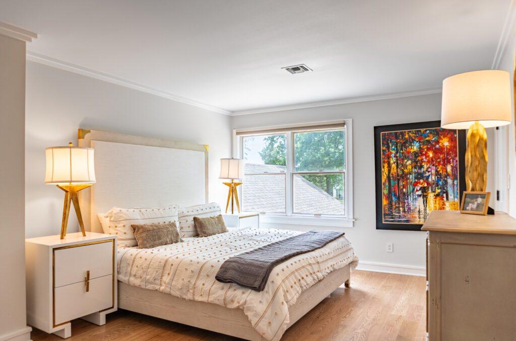 Bedroom with queen bed, bedside lamps, and framed wall art