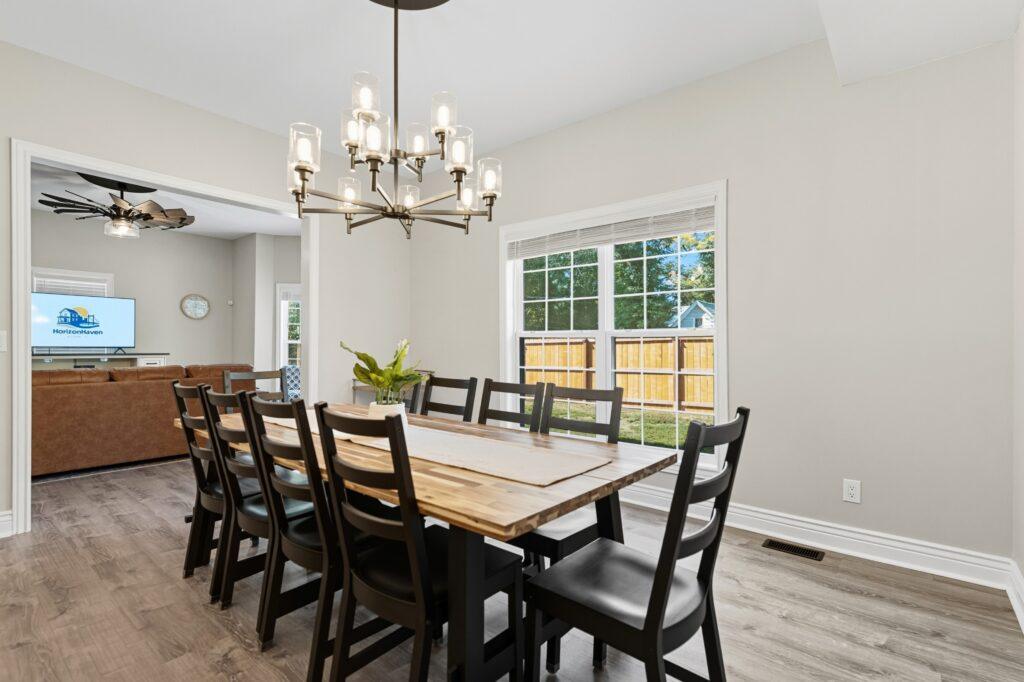 Dining room with wood table, chandelier, and large windows