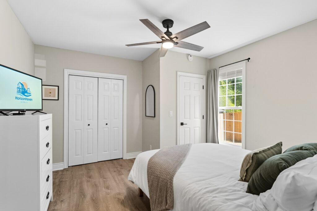 Guest bedroom with ceiling fan, double closets, and wood floors