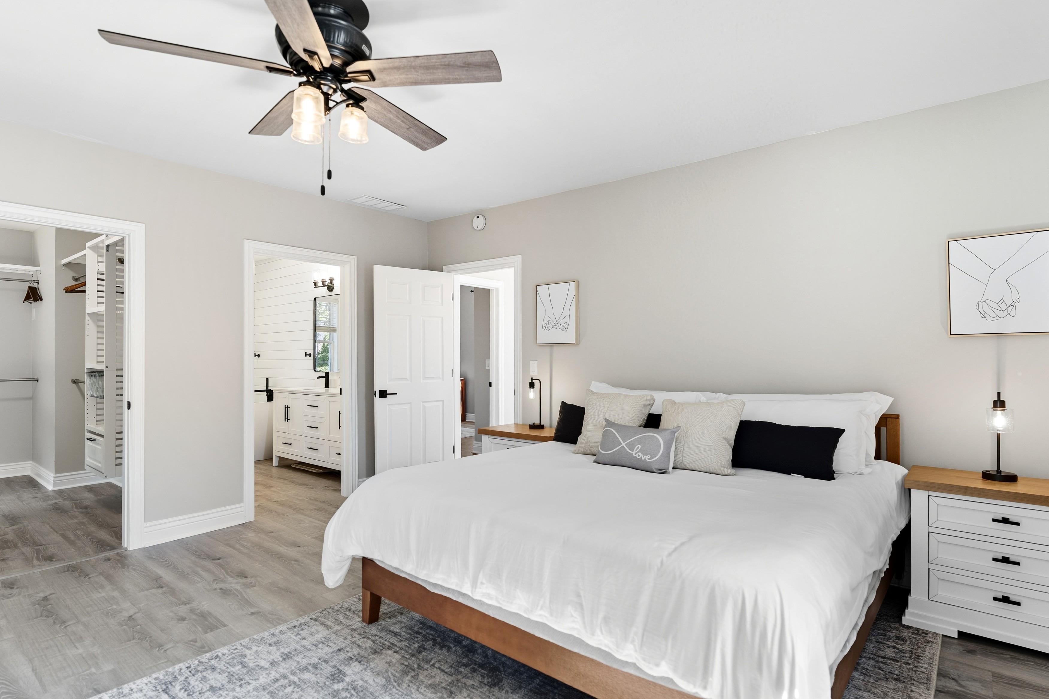 Guest bedroom with white bed, ceiling fan, and window views
