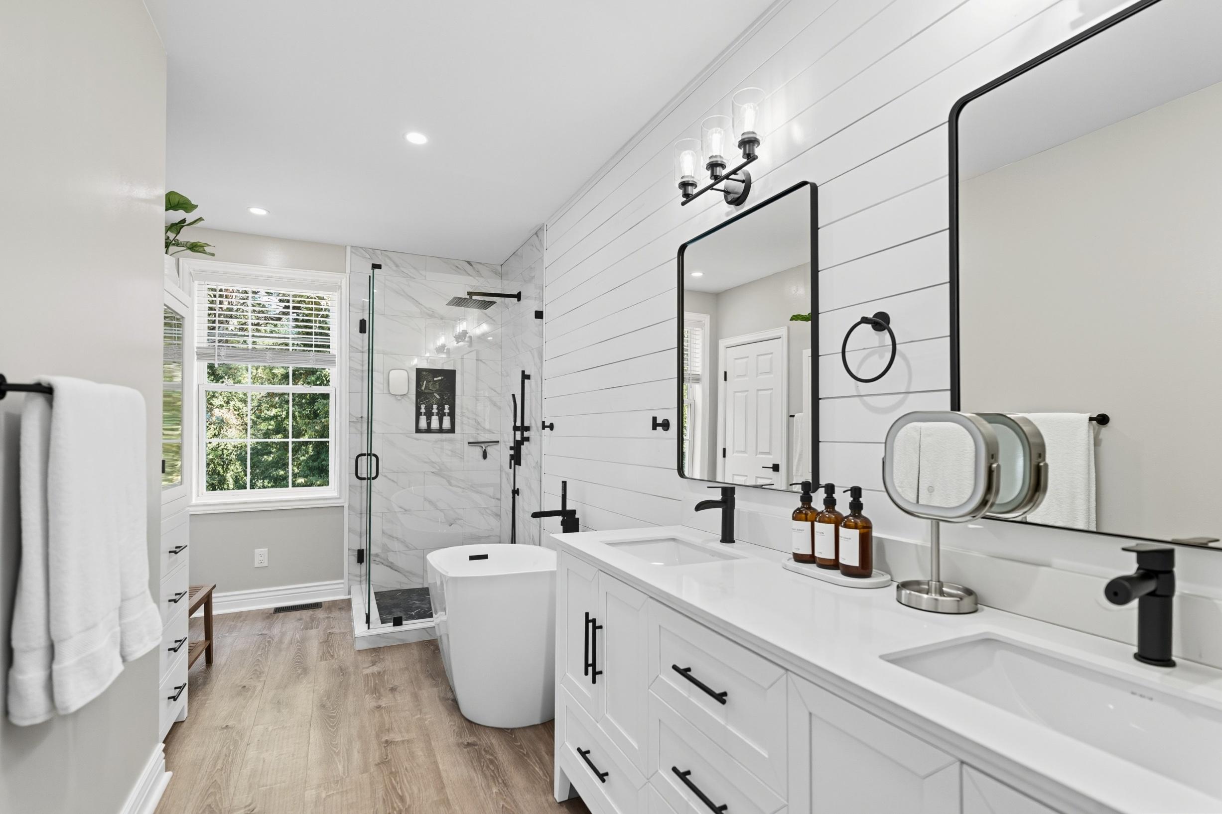 Bathroom with double vanity, framed mirrors, and walk-in shower