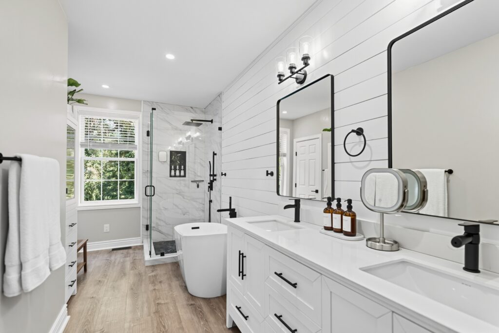 Bathroom with double vanity, framed mirrors, and walk-in shower