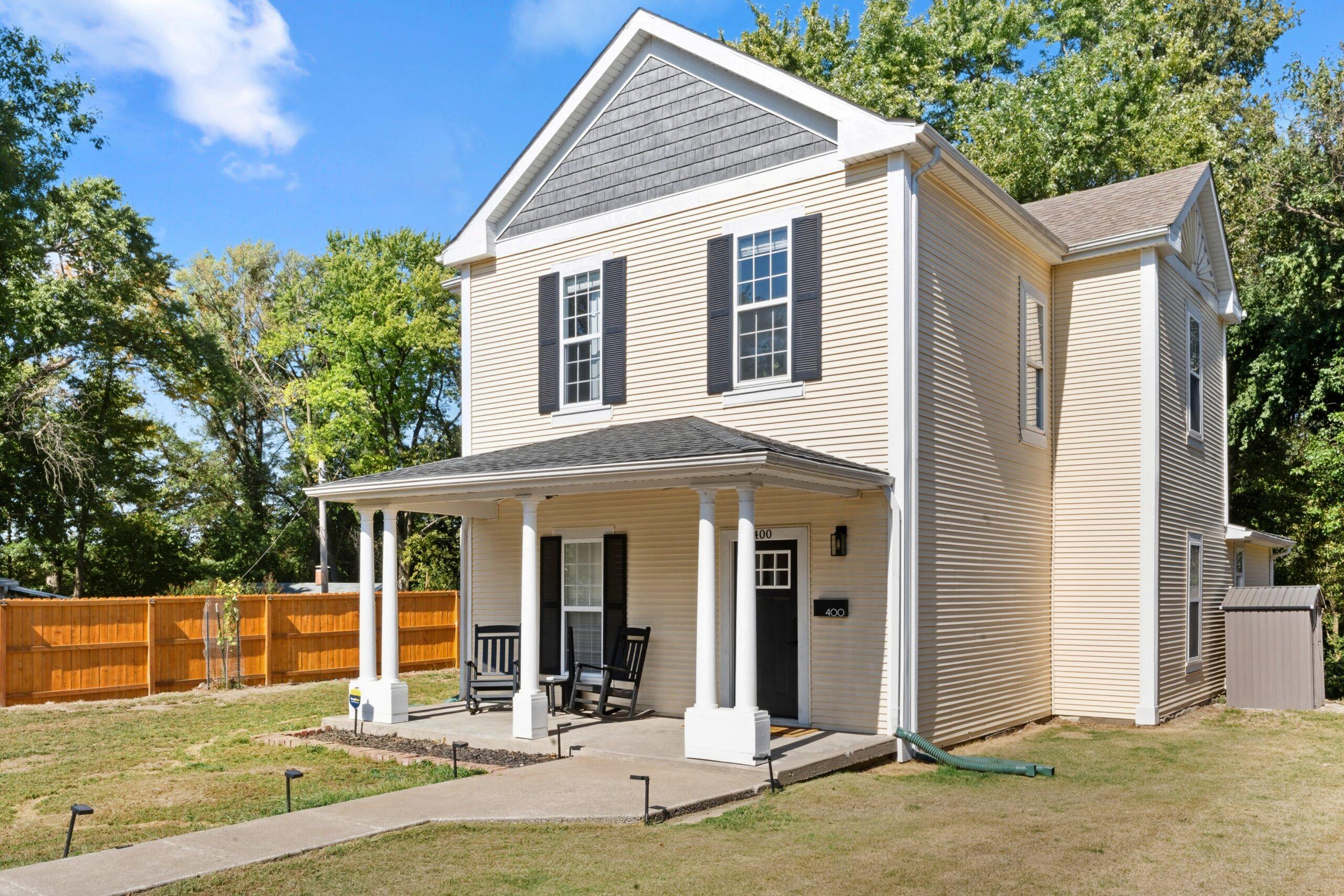 Two-story home exterior with covered front porch and landscaped yard