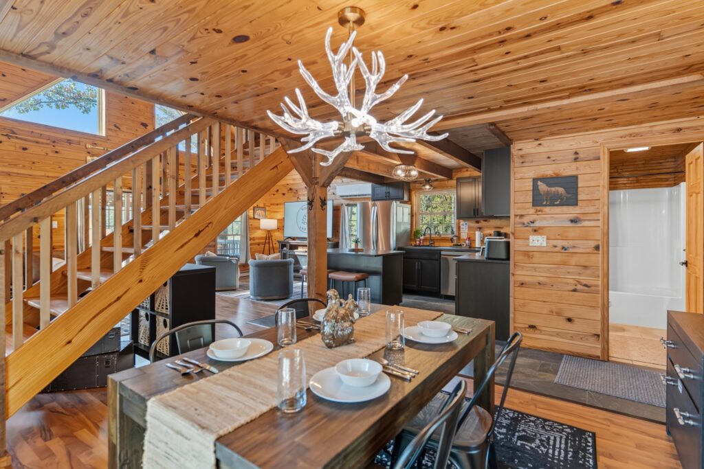 Log cabin dining room with chandelier and open staircase