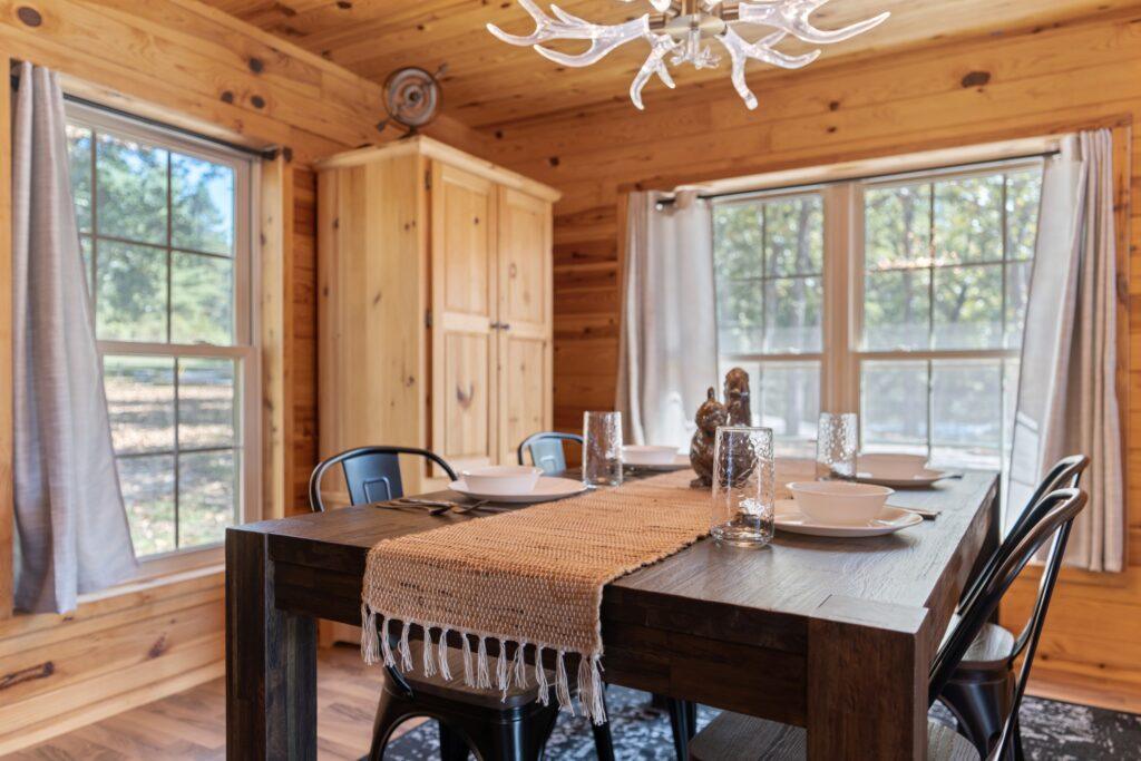 Dining area in log cabin with large windows and wooden table