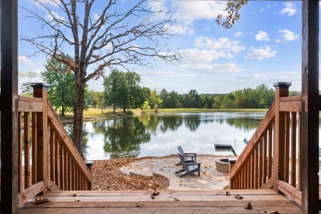 Deck stairs leading down to a pond surrounded by trees