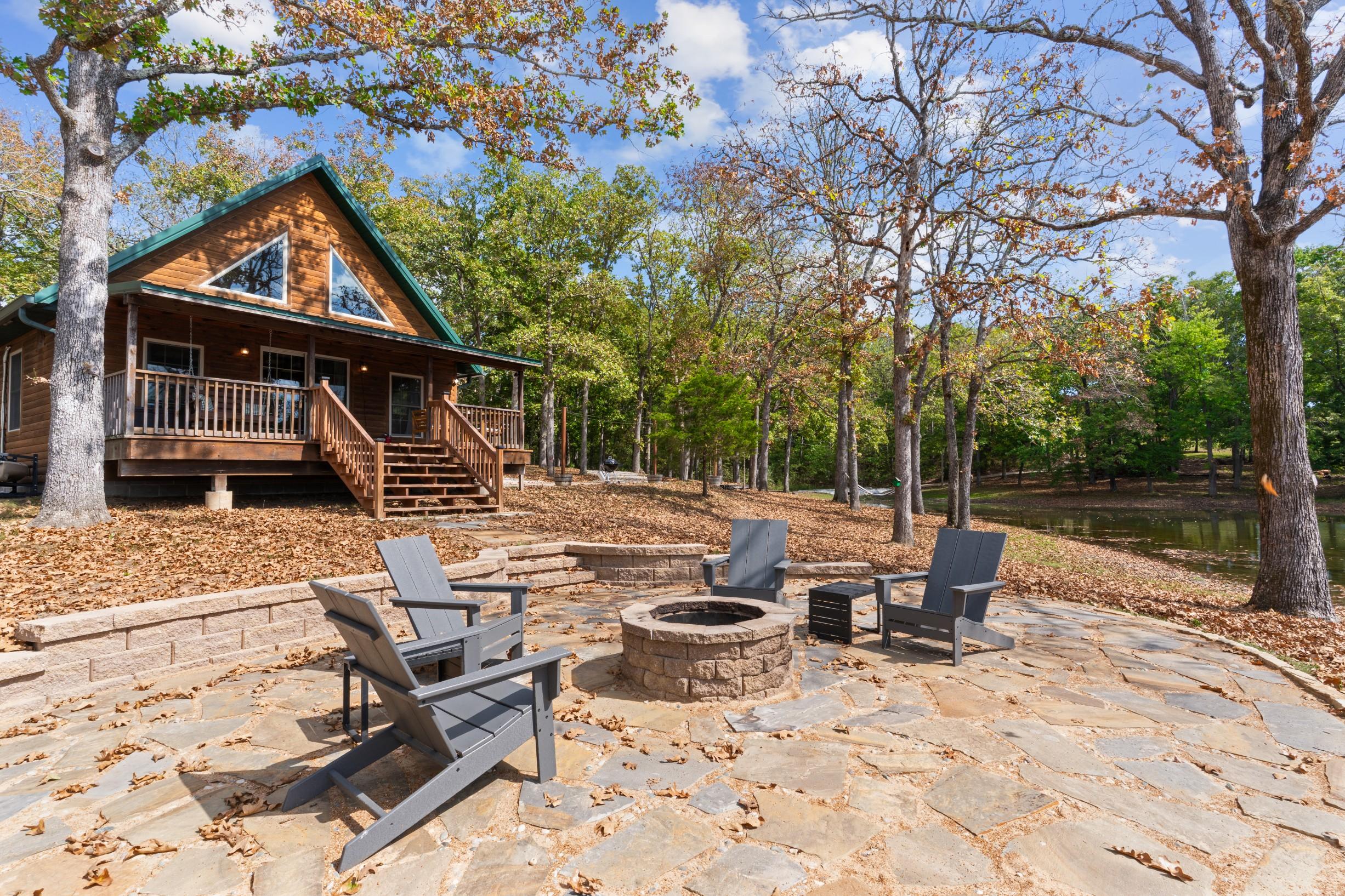 Outdoor firepit area with Adirondack chairs in wooded setting