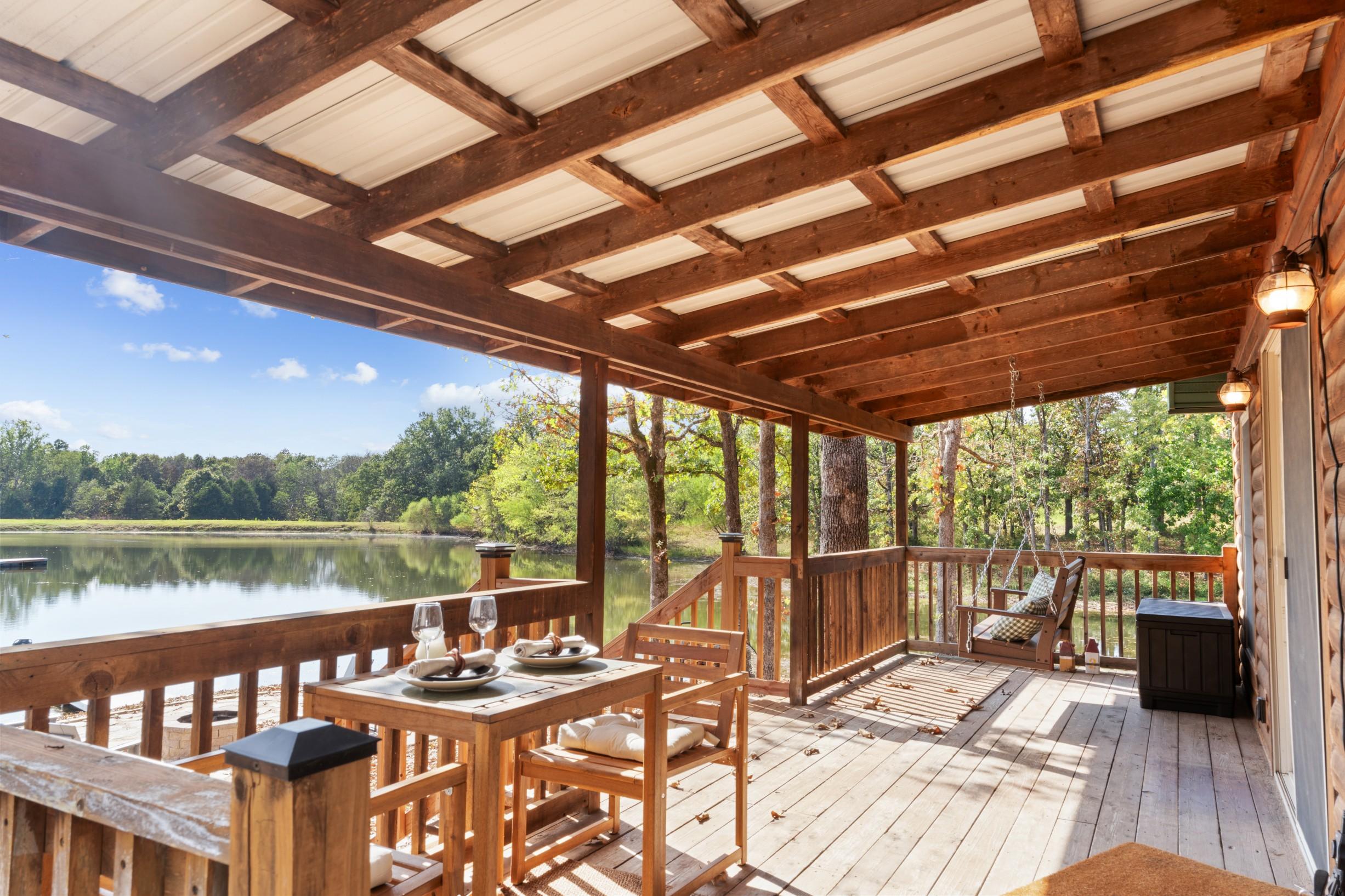 Covered wooden deck with dining table overlooking the water