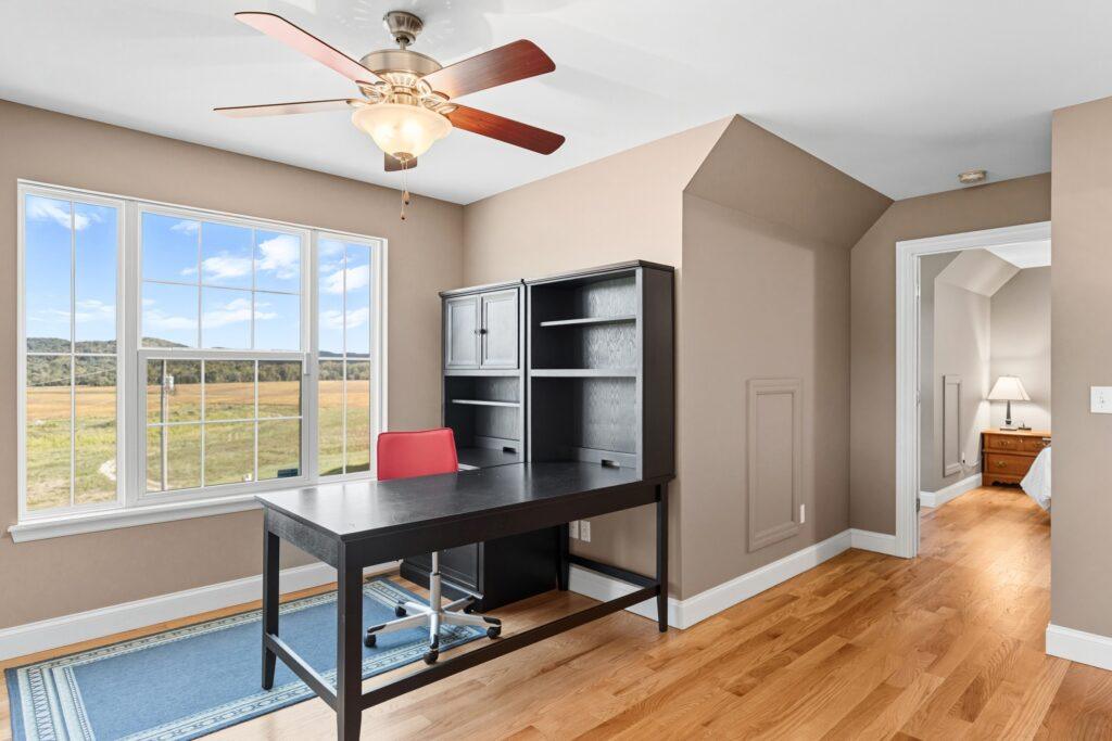 Home office with desk, shelving, and large windows