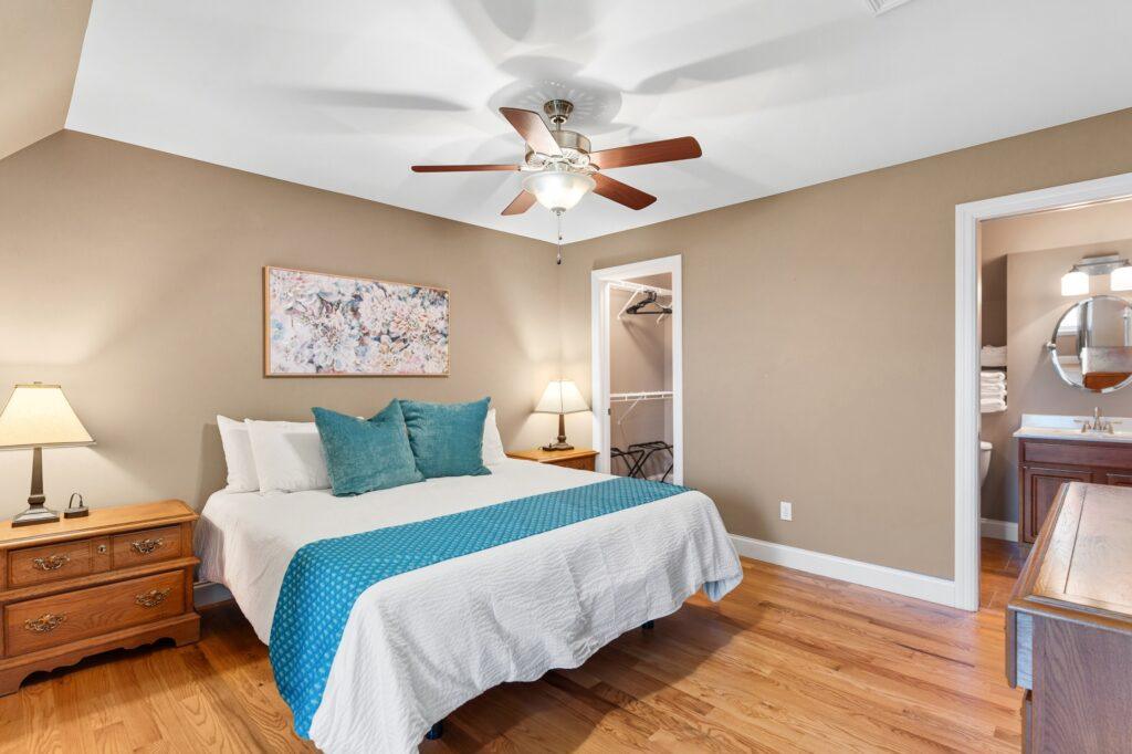 Bedroom with queen bed, ceiling fan, and neutral decor