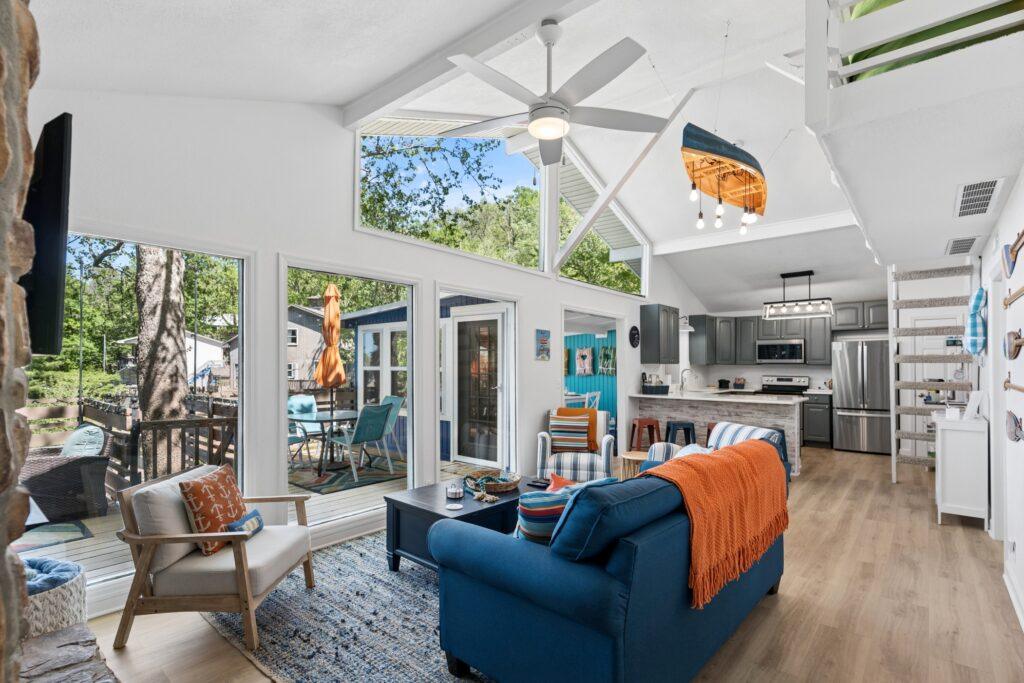 Living room with wide windows, a blue couch, a coffee table, and several chairs