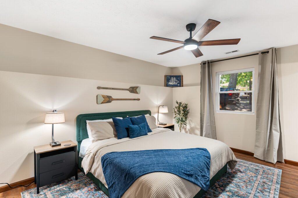 Bedroom with a bed flanked by two lamps with several oars on the wall for decoration
