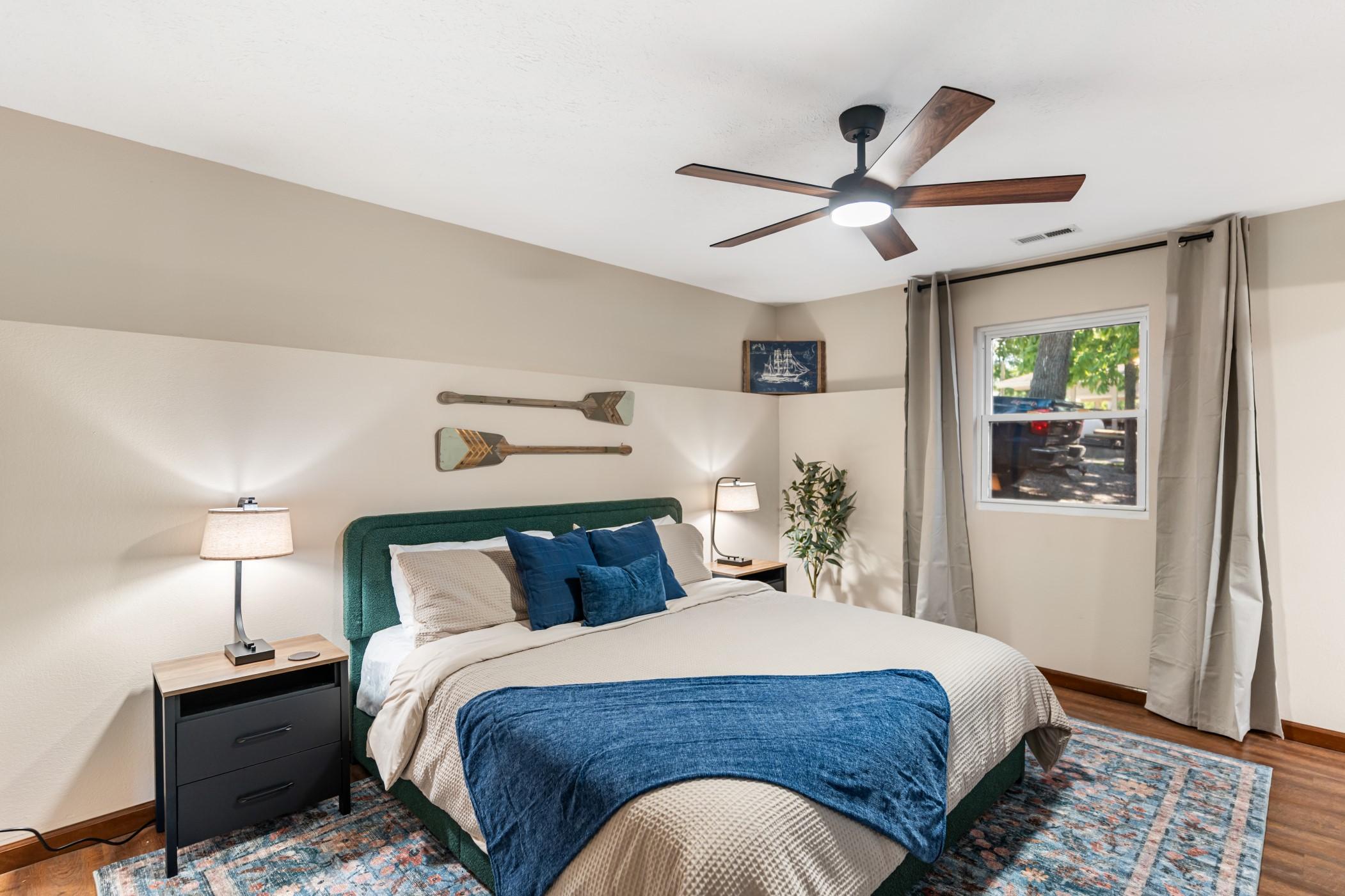 Bedroom with a bed flanked by two lamps with several oars on the wall for decoration