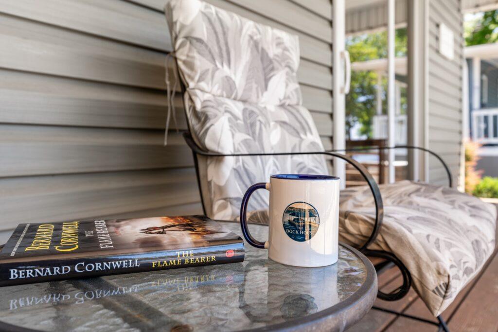 close-up of a side table with a book, a coffee mug, and a chair right next to it