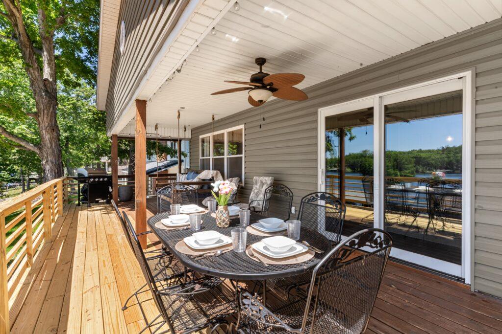Long porch with an outdoor dining table set for six and a large swinging bench in the background
