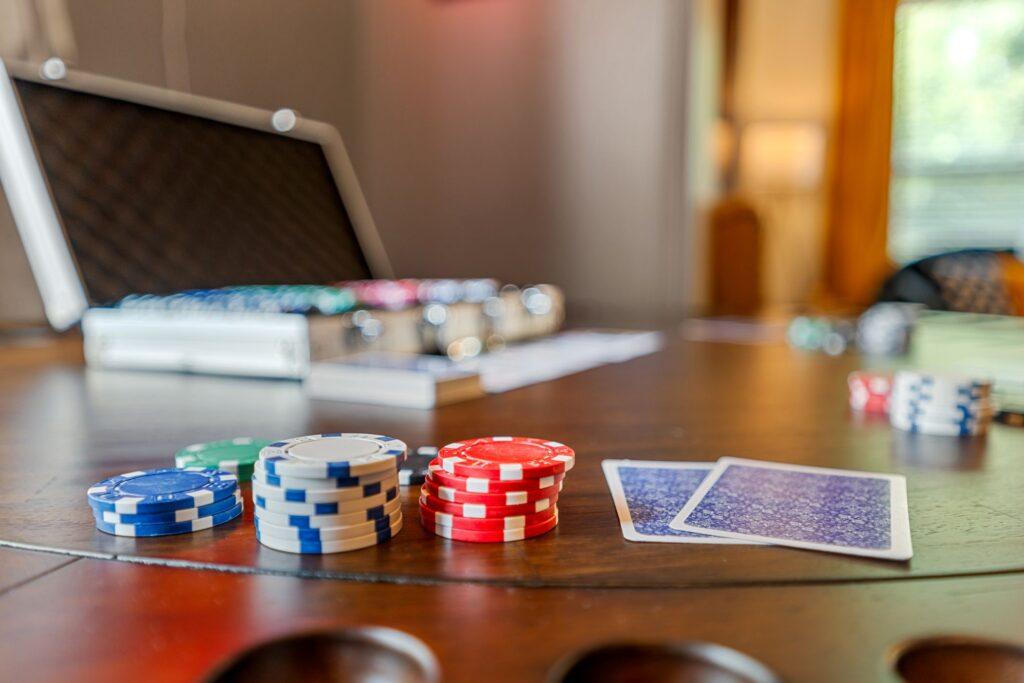 A close up of poker chips and cards on a table with a dealer's case in the background
