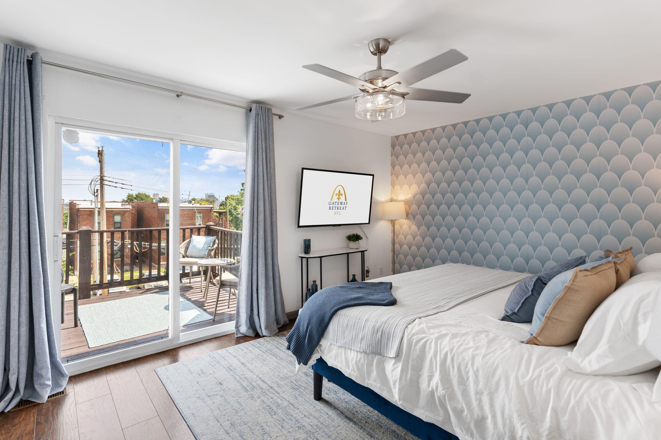 A bright bedroom with a sliding glass door leading to a balcony