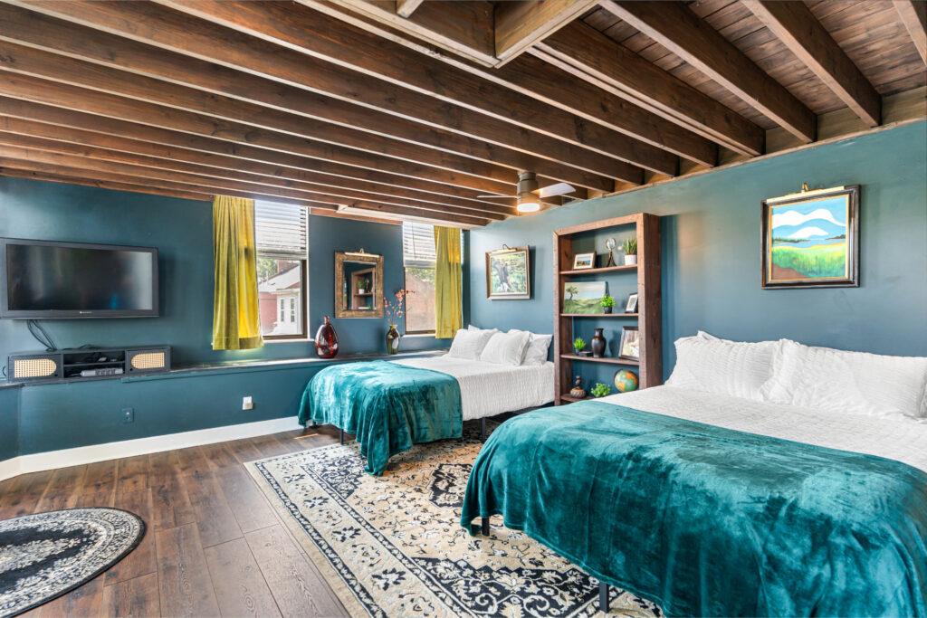 A large bedroom with two beds and a mounted TV