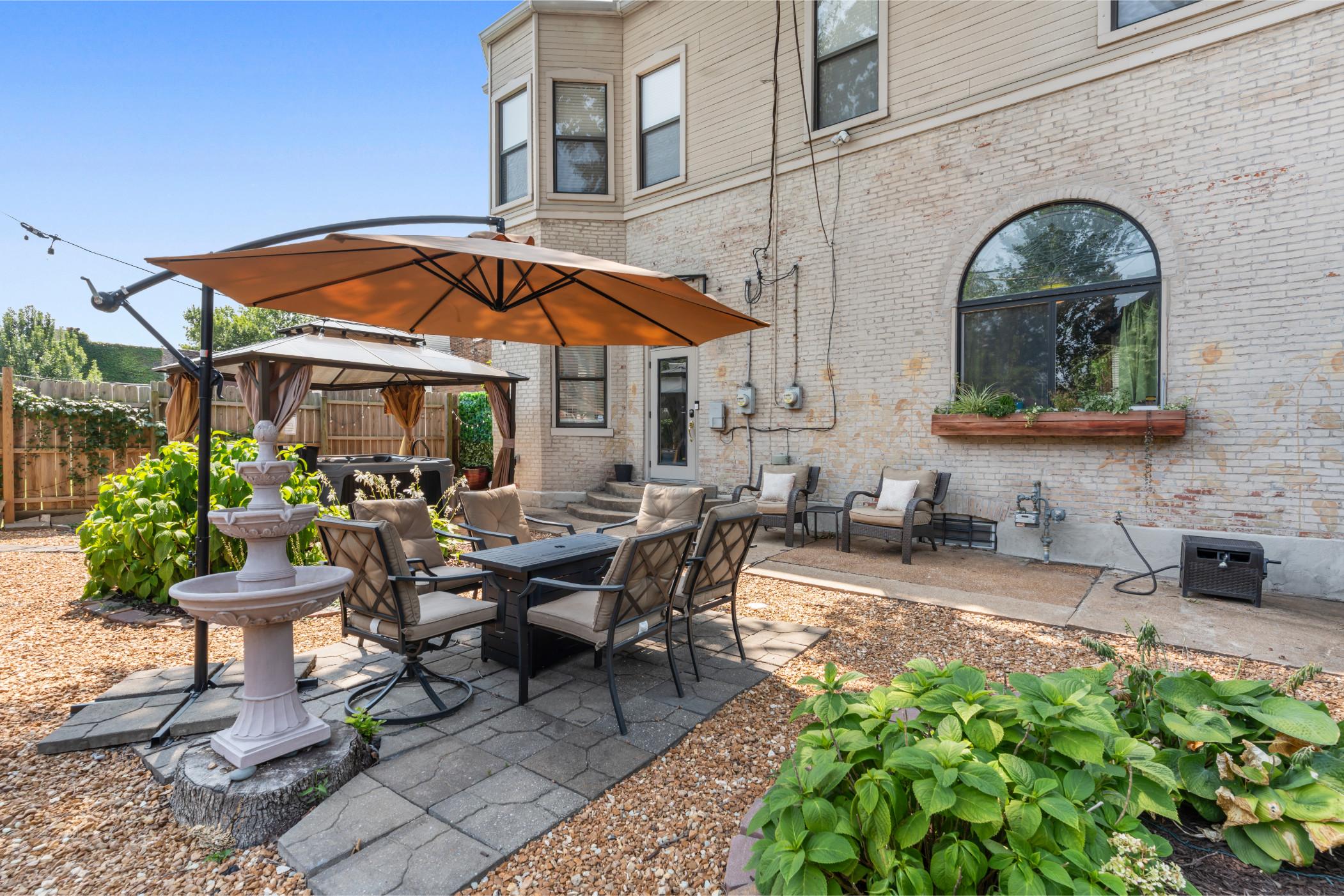Exterior shot of a patio featuring an outdoor table with chairs and an umbrella