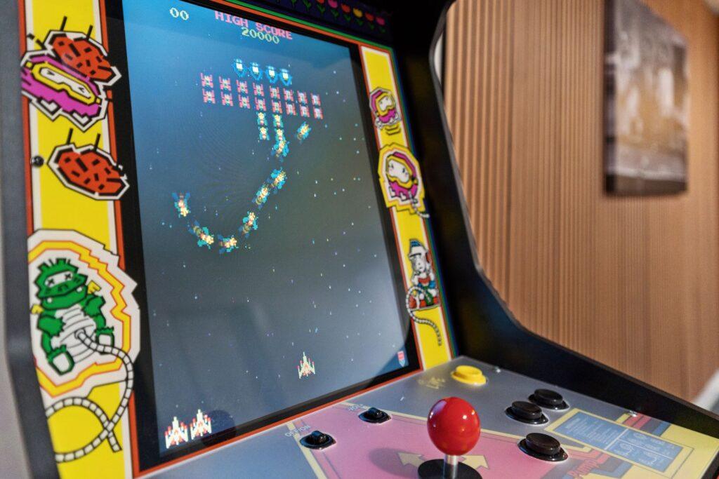 Close up shot of an arcade machine with an in-progress game of galaga on the screen