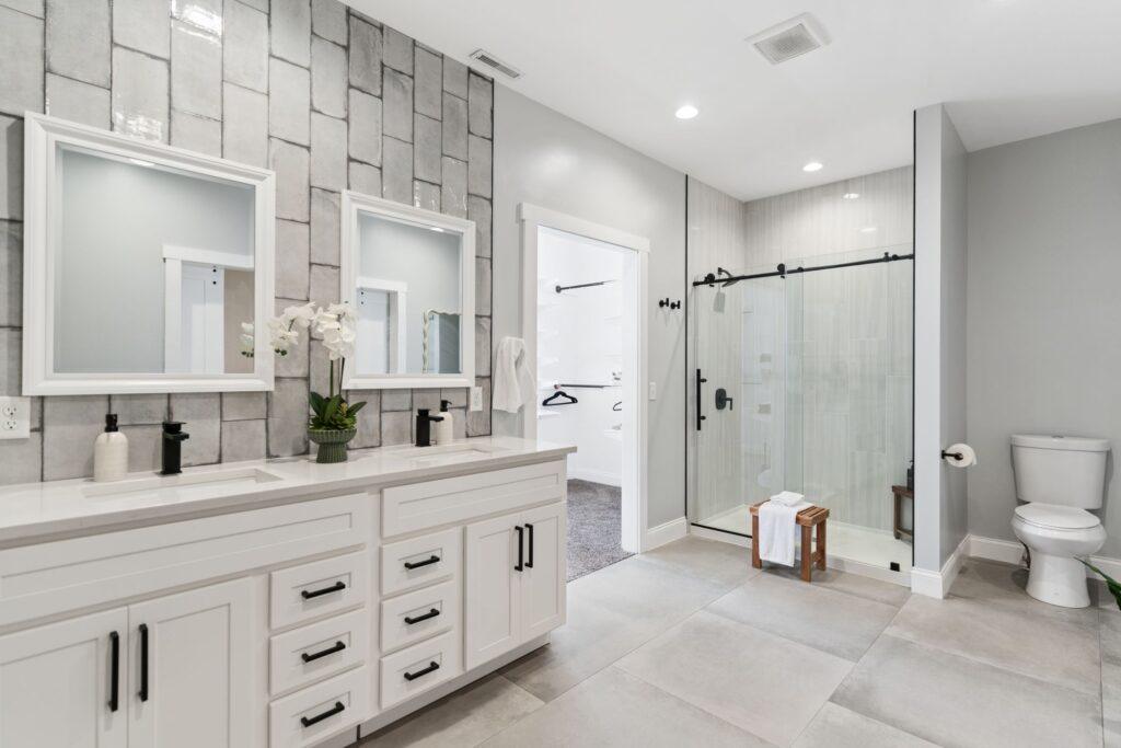 A large bright bathroom with two sinks and a sliding glass door walk-in shower