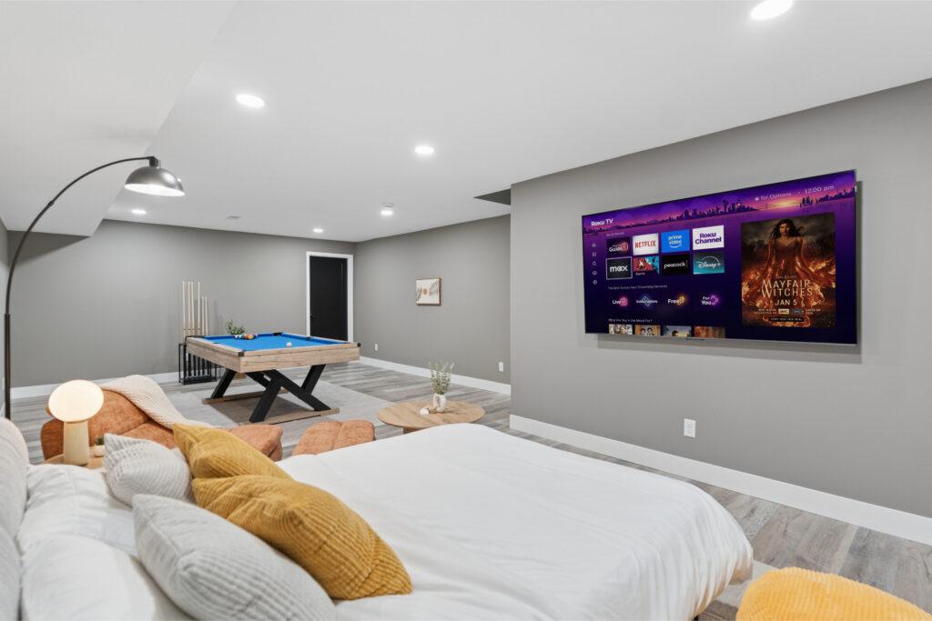 Basement bedroom / game room with a mounted TV and a pool table in the background